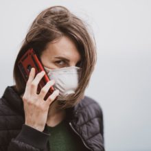 a woman talking on the phone with coronavirus mask