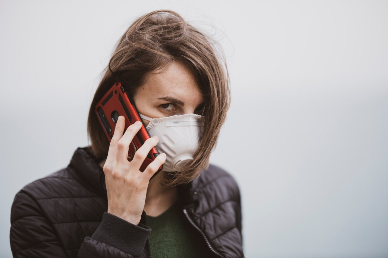 a woman talking on the phone with coronavirus mask