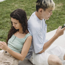 Crop focused multiethnic couple browsing internet on smartphones in town