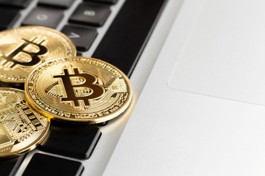 Varias monedas físicas de Bitcoin doradas sobre un teclado de laptop, simbolizando la intersección entre las criptomonedas y la tecnología informática.