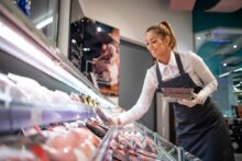 Carnicero cortando carne vacuna en una góndola de supermercado en Argentina