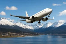 Avión volando sobre Ushuaia con montañas nevadas y el Canal Beagle de fondo