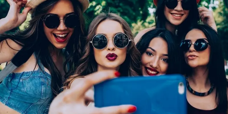 Grupo de amigas jóvenes tomando un selfie con gafas de sol y estilo urbano