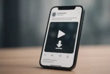 Teléfono móvil en primer plano con interfaz genérica mostrando icono de reproducción y flecha de descarga, sobre escritorio, sin logos ni texto.