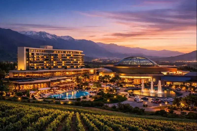 Vista panorámica del Hotel Casino Monticello en Chile al atardecer, con piscina, casino y montañas de fondo.