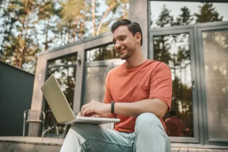 Hombre sentado al aire libre usando una notebook para revisar inversiones