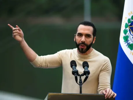 Nayib Bukele habla en un atril con micrófonos y la bandera de El Salvador al fondo.