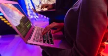 Personas usando laptops con código en pantalla en un ambiente con luces violetas y rojas
