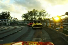 Vista desde un auto en una pista elevada con otros vehículos delante al atardecer