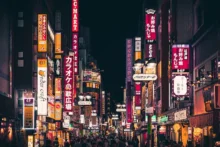 Calle urbana de noche con carteles luminosos en japonés, locales comerciales y peatones