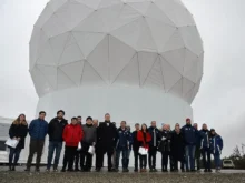 Grupo de personas frente a la gran cúpula blanca de la estación terrena en Tierra del Fuego