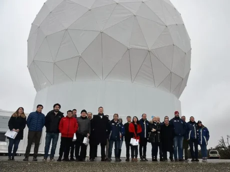Grupo de personas frente a la gran cúpula blanca de la estación terrena en Tierra del Fuego