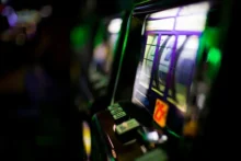 Primer plano de una máquina de slots encendida con luces verdes y fondo desenfocado