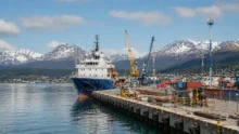 Muelle del Puerto de Ushuaia con un buque, grúas, contenedores y montañas nevadas al fondo