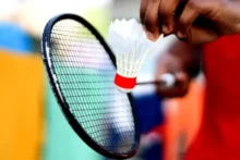 Mano sosteniendo un volante junto a una raqueta de bádminton antes del saque
