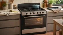 Cocina de pie negra y plateada en una cocina doméstica, con olla, cinta métrica y bandeja cerca