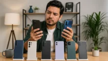 Hombre compara dos celulares frente a varios modelos exhibidos sobre una mesa