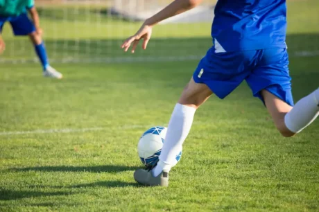 Futbolista con uniforme azul controla una pelota en una cancha de césped
