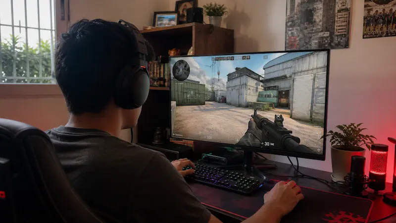 Joven jugando en PC con la caché de Counter-Strike en pantalla