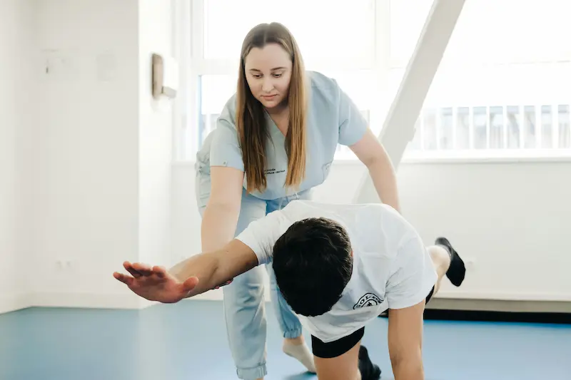 kinesiologa evaluando deportista Profesional de salud acompaña a un hombre durante un ejercicio de equilibrio