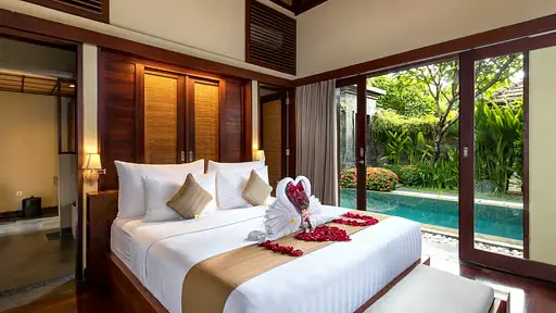 Bedroom in a tropical villa with a private pool, garden view and romantic decoration on the bed