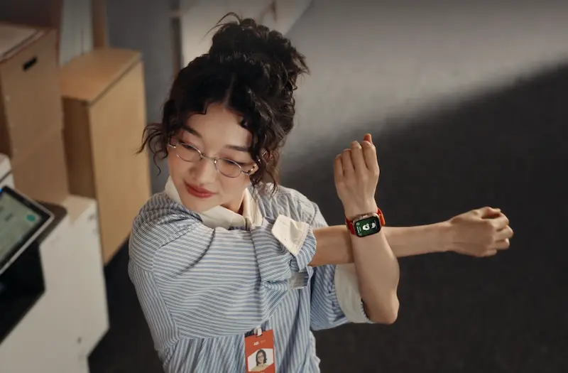 Frau mit Brille streckt den Arm und trägt eine Smartwatch in einem Innenraum