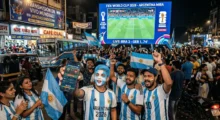 Hinchas argentinos con banderas frente a una pantalla del Mundial 2026 en una calle nocturna