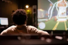 Persona sentada frente a una pantalla grande con una transmisión digital en vivo