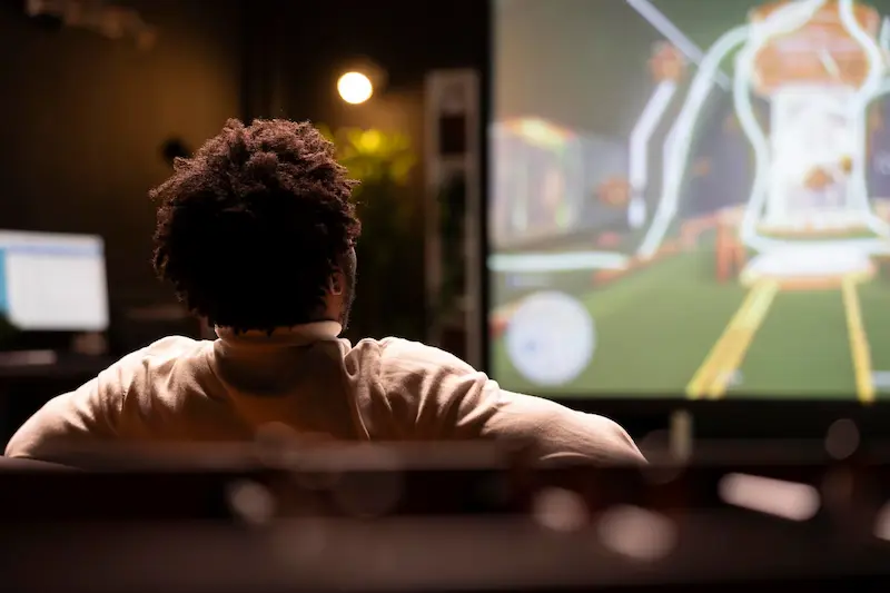 Persona sentada frente a una pantalla grande con una transmisión digital en vivo